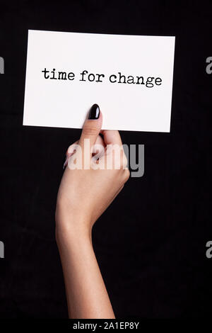 Hand, die eine weiße Karte auf schwarzem Hintergrund - Zeit für Veränderung Stockfoto