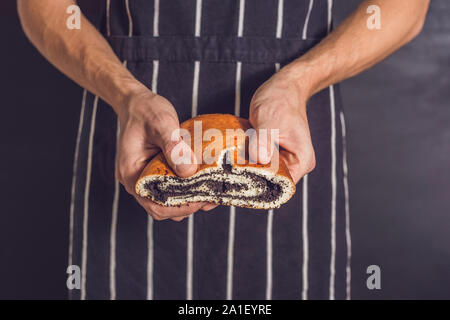 Rolle mit Mohn in den Händen eines Bäckers. Stockfoto