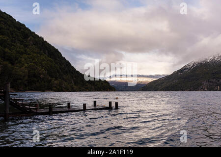 Szene von hölzernen Pier gegen die schneebedeckten Anden auf einem grauen Tag im Nationalpark Los Alerces, Patagonien, Argentinien Stockfoto