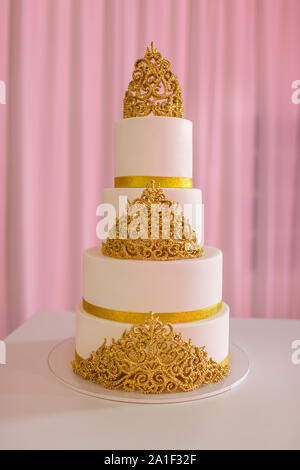 Hochzeitstorte, auf weißer Tisch. 3-Tiers in Elfenbein Fondant mit Pearl Spray und Gold Rosen aus Zucker Paste gesprüht. Hochzeitstorte mit Gold Stockfoto