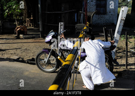 Indien, Madhya Pradesh, Nimad region, Khargone, Motorrad fahrer verletzen Verkehrsregeln während ein Bahnübergang Kreuzung mit geschlossenen Schranken Stockfoto