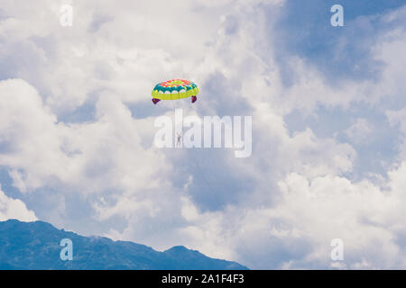 Junge Frau fliegt an einem Fallschirm unter den Wolken. Stockfoto