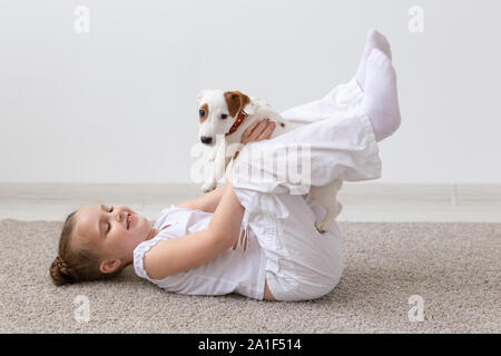 Kinder, Haustiere und Hunde Konzept - wenig liebenswert Kind Mädchen liegt auf dem Boden und spielen mit lustigen Welpen Jack Russell Terrier Stockfoto