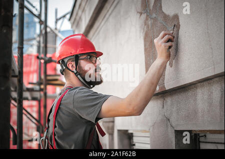 Mann Arbeiter auf Gerüst, die Arbeit an der Restaurierung der Fassade des alten Gebäudes durchführen. Reparieren und Renovieren Stockfoto