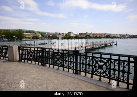 Zürich, Schweiz, 19. Juli 2019: Teil der Promenade und Boot Dock Zürich See mit blauer Himmel mit Wolken an einem sonnigen Tag und wenige Leute auf dem Dock. Stockfoto
