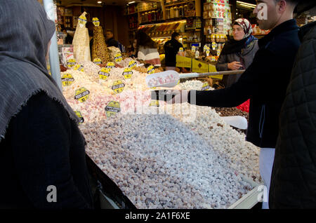 Istanbul, Türkei, März 07,2019: Verkäufer mit großen plastiklöffel setzt locum in Feld für den Kunden, der muslimischen Frau in Store verkaufen Turkish Delight Stockfoto