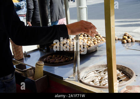 Stanbul, Türkei, 07. März 2019: Detail der Street Hersteller hinter der traditionellen Straße Warenkorb vending Holding Zangen Vorbereitung gegrillte Kastanien Stockfoto