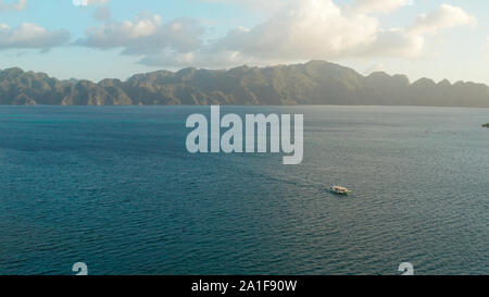 Luftaufnahme seascape Bucht mit Inseln und Berge Sonnenuntergang. Tour Boot im Meer. traditionellen philippinischen Holz- Auslegerboot, das die Banca genannt. Motorboot Kreuzung Ozean. Banca Boot auf den Philippinen Palawan Stockfoto