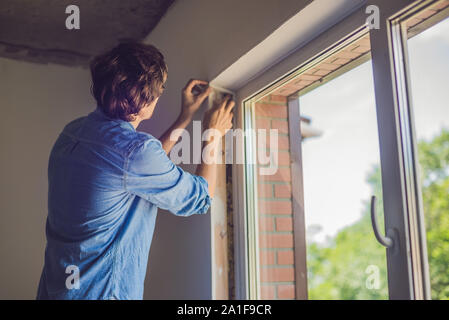 Mann in einem blauen Hemd das Fenster Installation. Stockfoto