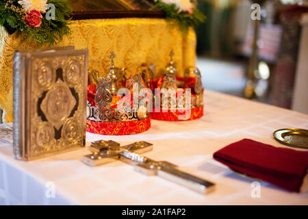 Hochzeit Dekoration in der Kirche. Orthodoxe Kirche Hochzeit Zubehör. Kronen und Kreuzigung. Bibel in Gold. Stockfoto