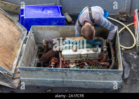 Mann bei der Arbeit auf seinem Boot, Motor Stockfoto