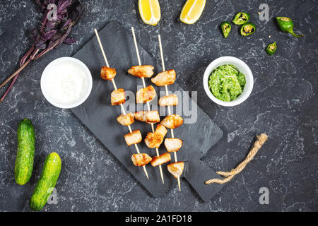 Gegrilltes Hähnchen auf Bambus Spieße auf einem schwarzen Stein Hintergrund. Ansicht von oben. Stockfoto