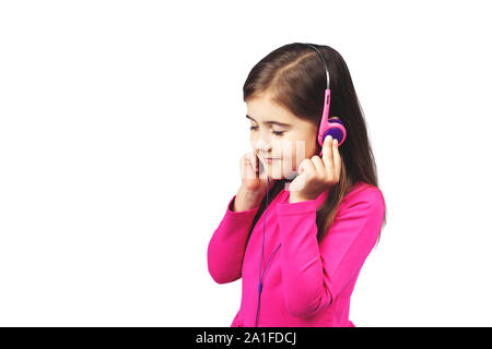 Kleine süße Mädchen Musik hören über Kopfhörer. Rosa Kleid. Auf den weißen Hintergrund isoliert. Konzept moderne Technologien, Kommunikation, Gadgets, etc. Stockfoto