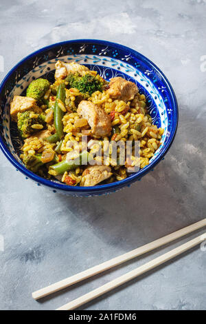 Reis mit Hühnerfleisch und Gemüse in eine Platte auf konkrete Tabelle Stockfoto
