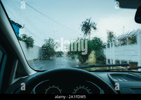 Die Windschutzscheibe eines Autos nass durch den Regen. Ein Auto an einem regnerischen Tag. Innenansicht, fahren mit kein Verkehr an einem kalten regnerischen Tag. Nasse Frontscheibe. Stockfoto