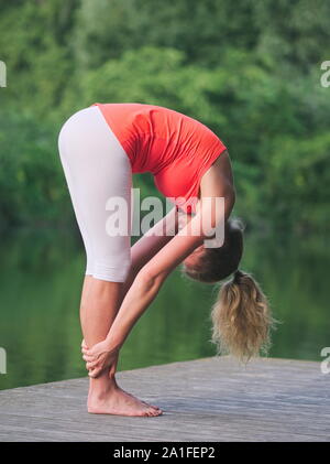 Frau in den 30er Jahren Yoga im Park auf einem Pier Stockfoto