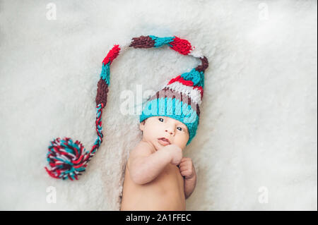 Neugeborenes Baby im Neuen Jahr gnome Cap liegt auf einer weißen Decke. Stockfoto