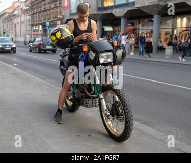 Belgrad, Serbien 29.August 2019: städtische Szene mit einem jungen Mann sitzen auf einem Motorrad auf einem Bürgersteig geparkt Stockfoto