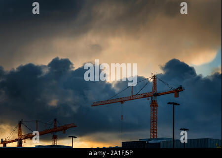 Unheilvolle Wolken den Himmel über eine Baustelle, wo zwei große Kräne Tower. Stockfoto