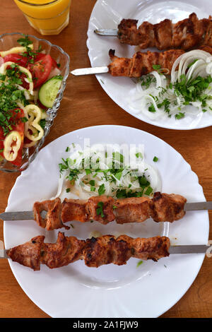 Gegrilltes Fleisch auf einem Spieß liegt auf einem Teller Stockfoto