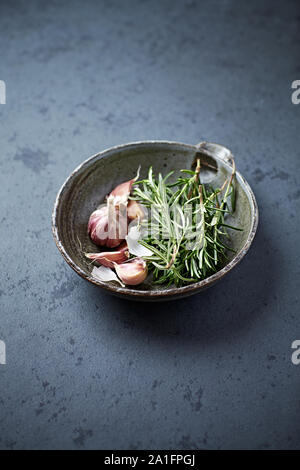 Frischer Rosmarin und Knoblauch in einer Schüssel aus Keramik Stockfoto