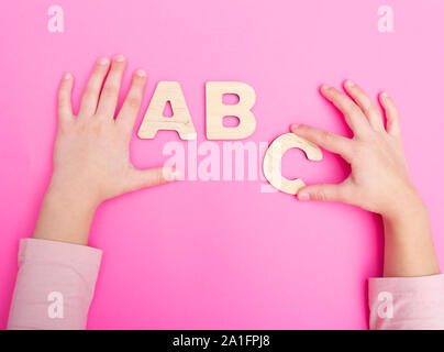 ABC Buchstaben in die Hände von Kind auf rosa Hintergrund. Stockfoto