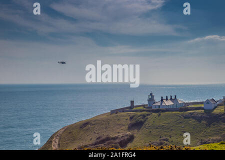 Küstenwache Hubschrauber über Anvil Point Lighthouse in Durlston Country Park, Swanage, Dorset, Großbritannien Stockfoto