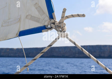 Nahaufnahme von Ende einer segeln Sie auf einer Segelyacht, Linien/Blätter und Knoten. Küste im Hintergrund Stockfoto