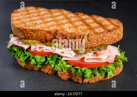 Handgefertigte lecker Türkei Sandwich mit Tomate, Salat und Gurken, auf schwarzem Hintergrund Stockfoto