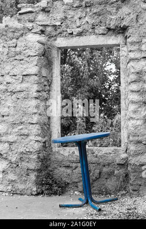 Eine alte Metall Tisch vor der Wand eines Hauses ruinieren. Eine künstlerische colorkey Design. Stockfoto
