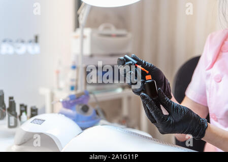 Flasche hellen Nagellack in Händen der Kosmetikerin. Friseur, Maniküre. Schönheit und Self Care Thema. Stockfoto