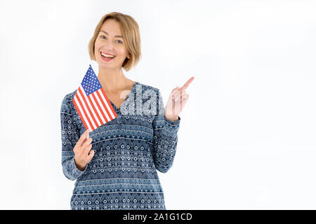 Schöne Frau mit der Flagge der Vereinigten Staaten von Amerika zeigt mit dem Finger nach rechts, stehend auf einem hellen Hintergrund. Stockfoto