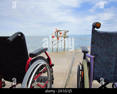 Rollstühle in einem zugänglichen Strand für den Transport von Menschen mit Behinderungen in das Wasser. Stockfoto