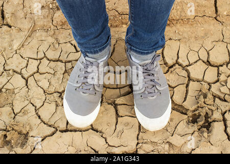 Füße in Turnschuhen und Jeans stehend auf dem Boden gerissen Stockfoto