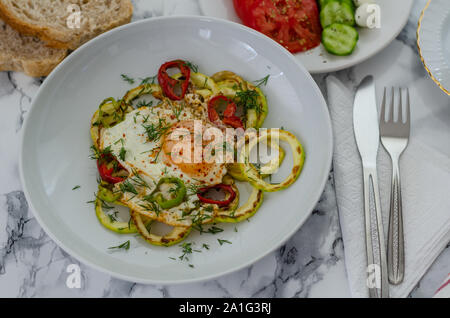 Gesundes Frühstück mit Spiegelei und Pfeffer auf gegrillten Zucchini. Es gibt in Scheiben geschnittenen Tomaten, Gurken, Käse und türkischen Tee mit Frühstück auf Marmor tab Stockfoto