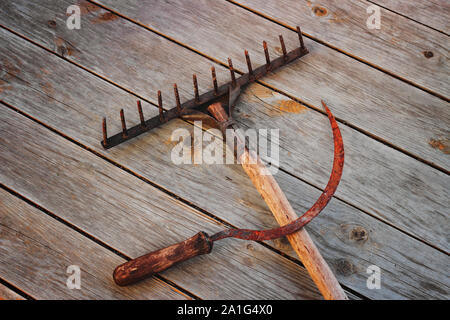 Sichel und die Heugabel auf dem hölzernen Hintergrund, Konzept Stockfoto