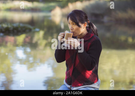 Eine koreanische Frau genießt eine Tasse Kaffee auf einen Tag fallen in Spokane, Washington. Stockfoto