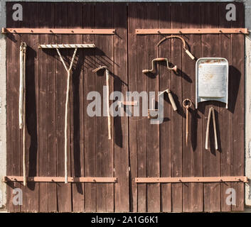 Alten rostigen landwirtschaftliche Werkzeuge auf alten Holztüren als Dekoration. Stockfoto