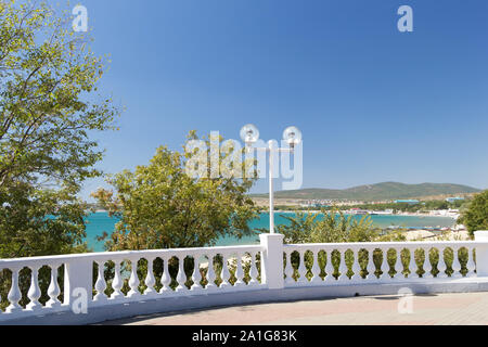 Blick auf Marine durch weiße Steinbrüstung von der Promenade an einem sonnigen Tag in Velvet Saison. Dekorative Baluster, runde Laternen, grünen Bäumen. Stockfoto