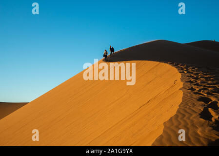 Menschen auf Sanddünen bei Sonnenuntergang in der Wüste von Marokko Stockfoto