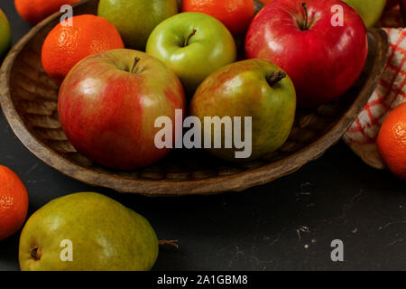 Äpfel, Birnen und Orangen Mandarinen auf Holz geschnitzte Schüssel - closeup Detail Stockfoto