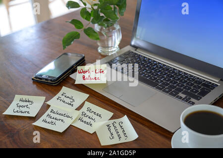 Work life Balance, wiegen Worte auf Haftnotizen auf einer hölzernen Schreibtisch mit einem Laptop geschrieben, ausgewählte konzentrieren, enge Tiefenschärfe Stockfoto