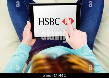 Benon, Frankreich - Januar 21, 2018: Frau sitzt im Schneidersitz auf dem Sofa und Verwenden Sie das Touchpad, um Informationen über hsbc Unternehmen HSBC Logo sehen, ist Stockfoto