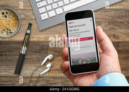 Benon, Frankreich - Januar 21, 2018: Der Mensch im Büro mit seinem Smartphone auf Informationen zu HSBC Bank Unternehmen berät er den Service Registrierung pa siehe Stockfoto