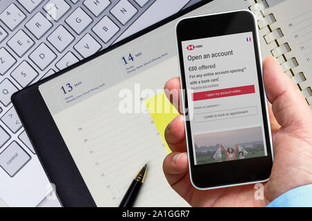 Benon, Frankreich - Januar 21, 2018: Der Mensch im Büro mit seinem Smartphone auf Informationen zu HSBC Bank Unternehmen berät er den Service Registrierung pa siehe Stockfoto