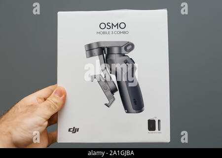 Paris, Frankreich - Spe 12, 2019: der Mensch hand mit neuen Karton verpackung des DJI Osmo Mobile3 Combo smartphone Falten Gimbal für filmische und Foto Erfahrungen - grauer Hintergrund Stockfoto