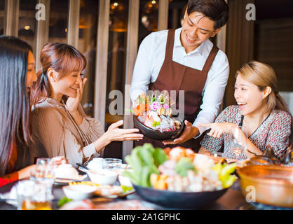 Kellner Meeresfrüchte bringen und mit einer Gruppe von Freunden im Restaurant. Stockfoto