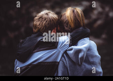 Die Nahaufnahme der Rücken der jugendlichen Mädchen und Jungen umarmen draussen in der Natur. Stockfoto