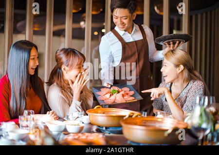 Gerne kellner Rindfleisch Scheiben bringen und mit einer Gruppe von Freunden im Restaurant. Stockfoto