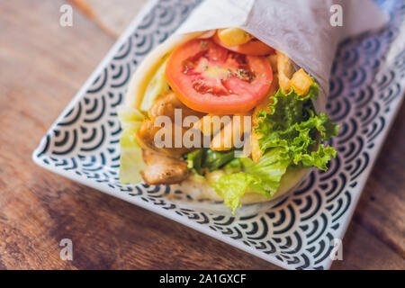 Griechische Gyros in pita Brot auf einem hölzernen Hintergrund gewickelt. Griechische küche Konzept. Stockfoto